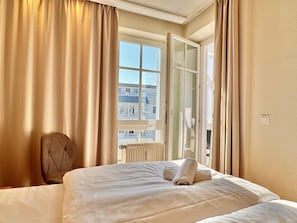 A hotel room with a bed, a chair, and a window with curtains. - Ferienwohnung in Sellin mit Balkon in Sudostlage (Sellin)