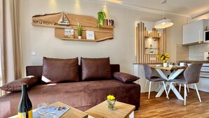 Ein modernes Wohnzimmer mit einem braunen Sofa, einem Holztisch und einem Essbereich mit einem weißen Tisch und Stühlen.