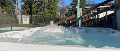 Un jacuzzi con fuente de agua, rodeado por una valla y árboles.