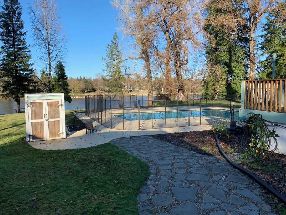 A backyard with a swimming pool, a wooden shed, and a stone pathway.