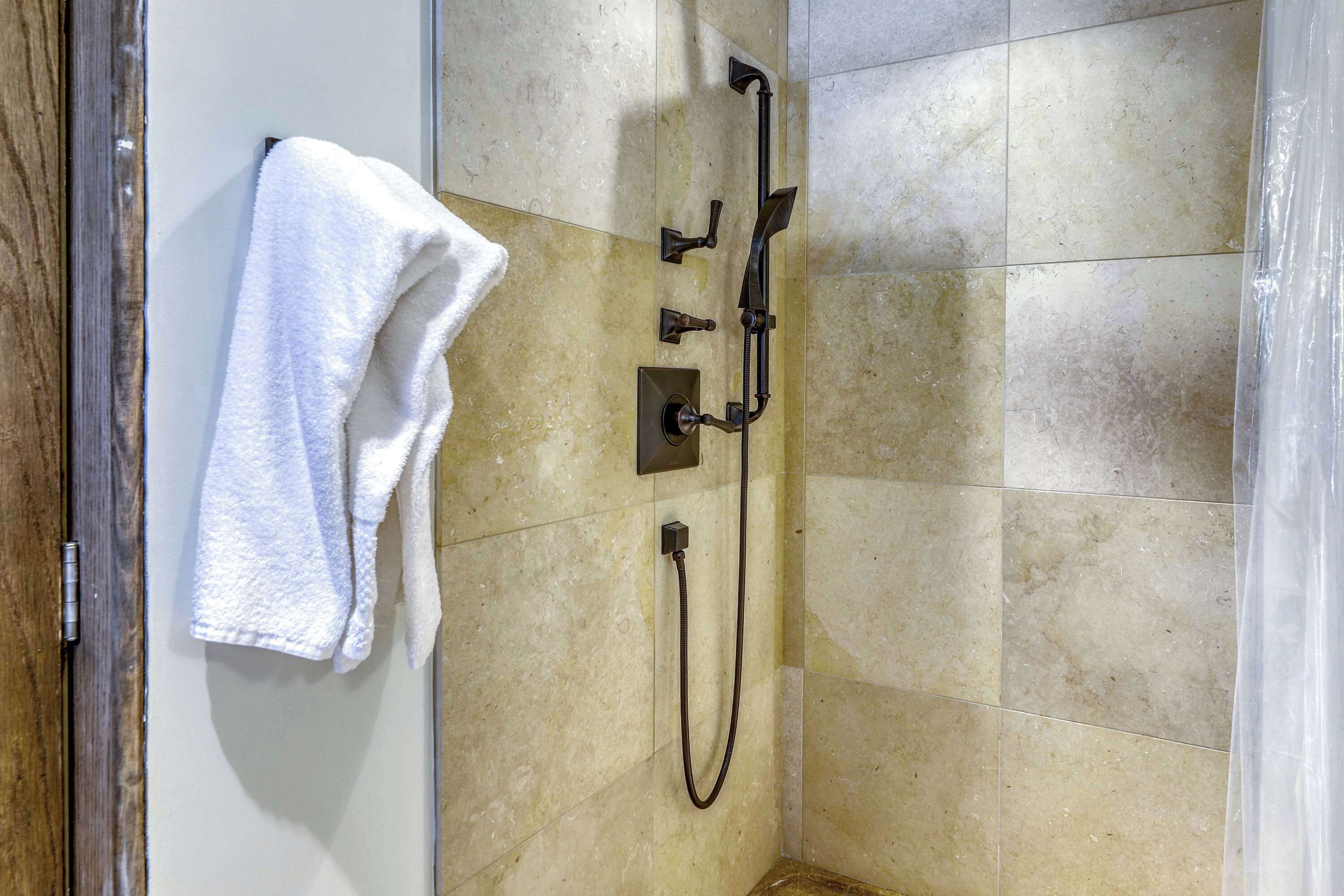 A bathroom with a shower, a towel rack, and a wall-mounted control panel.