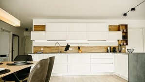 Uma cozinha moderna com armários brancos, bancada de madeira e um espaço de refeições com mesa e cadeiras.