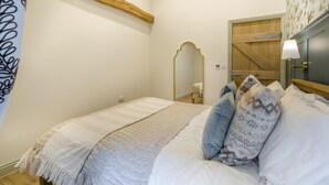 Een slaapkamer met een bed, een houten hoofdbord, een spiegel en een deur met een houten paneelmotief.