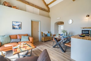 A spacious living area with a sofa, coffee table, dining table, and kitchen area with a microwave. - 2 Bed in Watermillock (oc-p36900) (Ullswater)