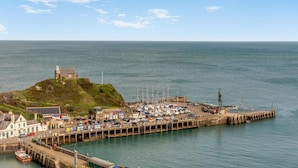 A coastal town with a historic building on a hill, a marina with boats, and a pier extending into the water. - 3 Bed in Ilfracombe (oc-h36896) (Ilfracombe)