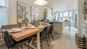 Eine moderne Küche mit Essbereich, mit einem Holztisch, schwarzen Stühlen und einer Pendelleuchte.
