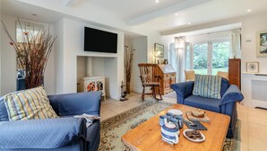 A living room with a fireplace, a television, and a dining area with a table set for two. - 4 Bed in Beckley (oc-s34808) (Beckley)
