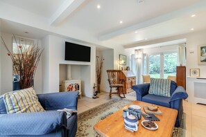 A living room with a fireplace, a television, and a dining area with a table set for two. - 4 Bed in Beckley (oc-s34808) (Beckley)