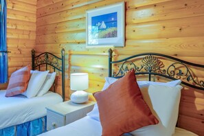 A wooden cabin room with two beds, a nightstand, a lamp, and a framed picture on the wall. - 3 Bed in Kenwick (oc-l36924) (Legbourne)