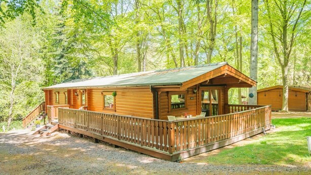 A wooden cabin with a porch, a deck, and a gravel driveway. - 3 Bed in Kenwick (oc-l36924) (Legbourne)