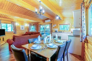 A wooden cabin interior with a dining area, sofa, kitchen, and a TV. - 3 Bed in Kenwick (oc-l36924) (Legbourne)