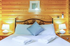 A wooden-paneled room with a bed, two bedside lamps, a framed picture on the wall, and a thermostat. - 3 Bed in Kenwick (oc-l36924) (Legbourne)