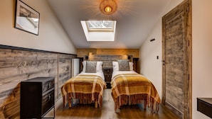 A bedroom with two beds, a skylight, wooden beams, and a wardrobe. - Central Chamonix Apartment With Views (Chamonix-Mont-Blanc)