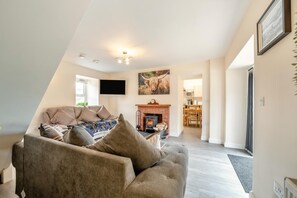 Ein Wohnzimmer mit einer Couch, einem Kamin und einem Fernseher.