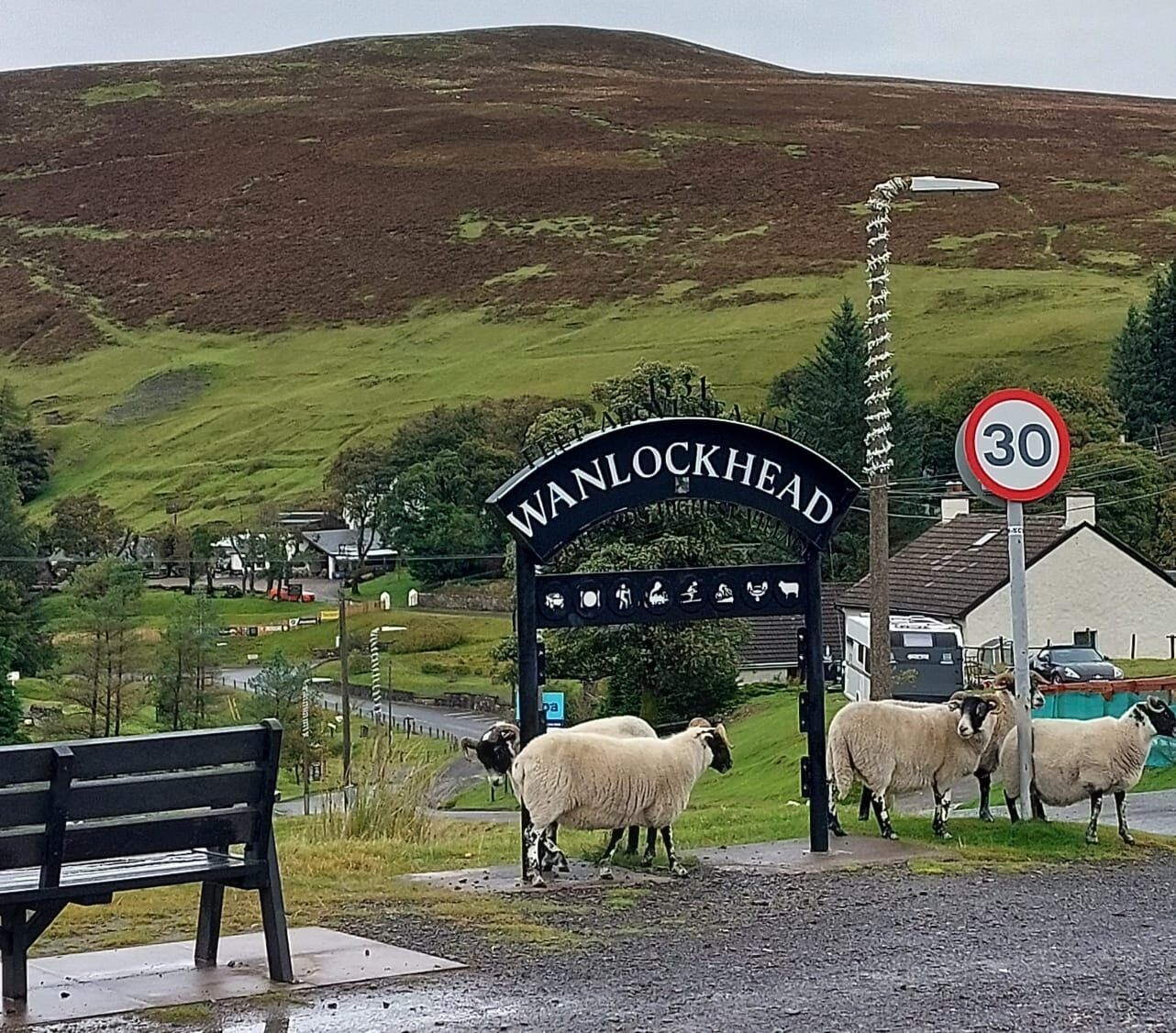 A rural setting with a sign reading 'WANLOCKHEAD' and a speed limit sign of 30.