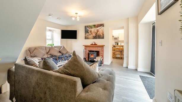 A living room with a sofa, a fireplace, and a television. - 3 Bed in Wanlockhead (oc-g36354) (Wanlockhead)