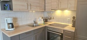 A modern kitchen with a built-in oven, a coffee maker, and a sink. - Geschmackvoll Eingerichtete Ferienwohnung mit Balkon in Sellin (Sellin)
