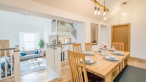 A spacious living area with a dining table set for four, a staircase leading to an upper floor, and a view of the outdoors. - 3 Bed in Dunning (oc-t35973) (Dunning)