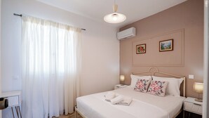 Un dormitorio ordenado con cama, mesitas de noche, un escritorio y una silla.