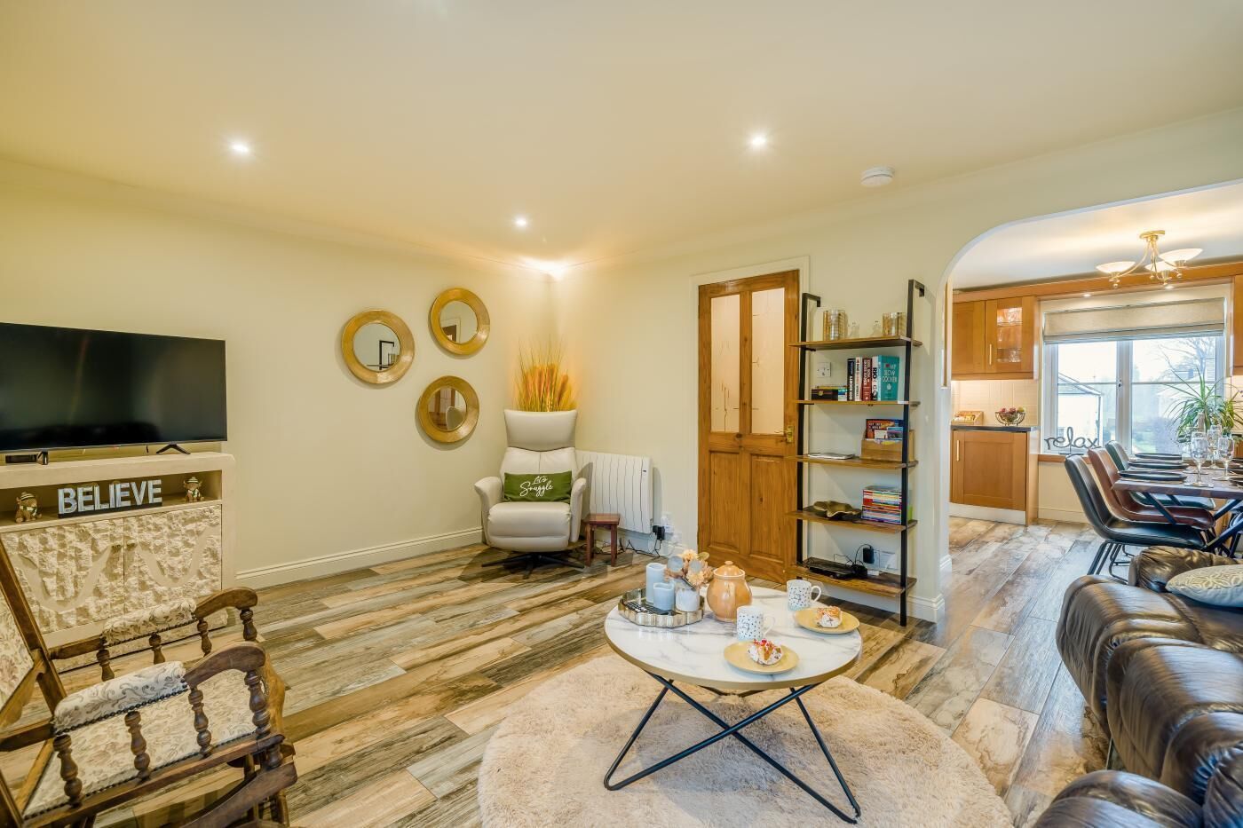 A living room with a TV, a fireplace, a dining area, and a kitchen.