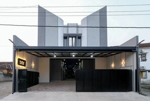 Un edificio moderno con entrada cubierta, un cartel que dice 'Easy Stay' y un camino pavimentado que lleva a la puerta.