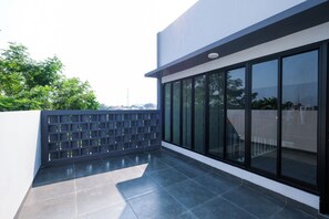 Un edificio moderno con fachada de vidrio, un patio con baldosas y una cerca de metal.