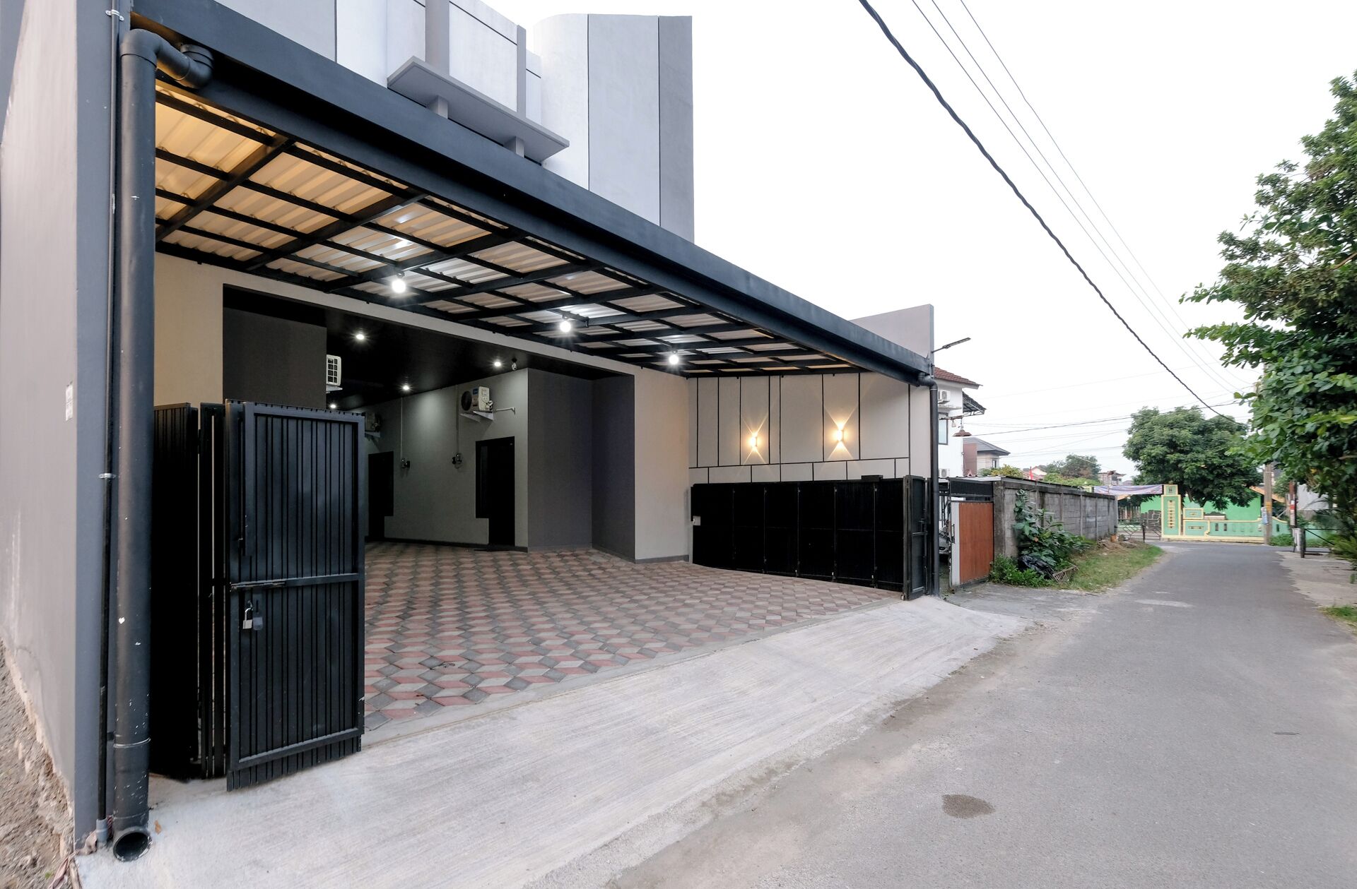 Un bâtiment moderne doté d’une entrée abritée, d’une allée carrossable dallée et d’un espace de stationnement clos.