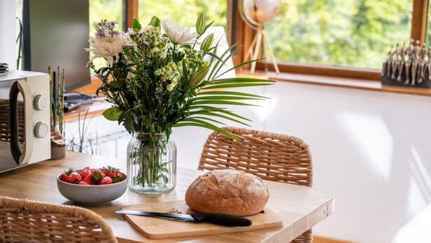 A dining table with a bowl of strawberries, a loaf of bread, and a vase of flowers. - 1 Bed in Mosedale (oc-b37510) (Mosedale)