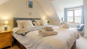A bedroom with a bed, bedside tables, a lamp, a painting, and a window. - 4 Bed in Redruth (oc-06457) (Portreath)