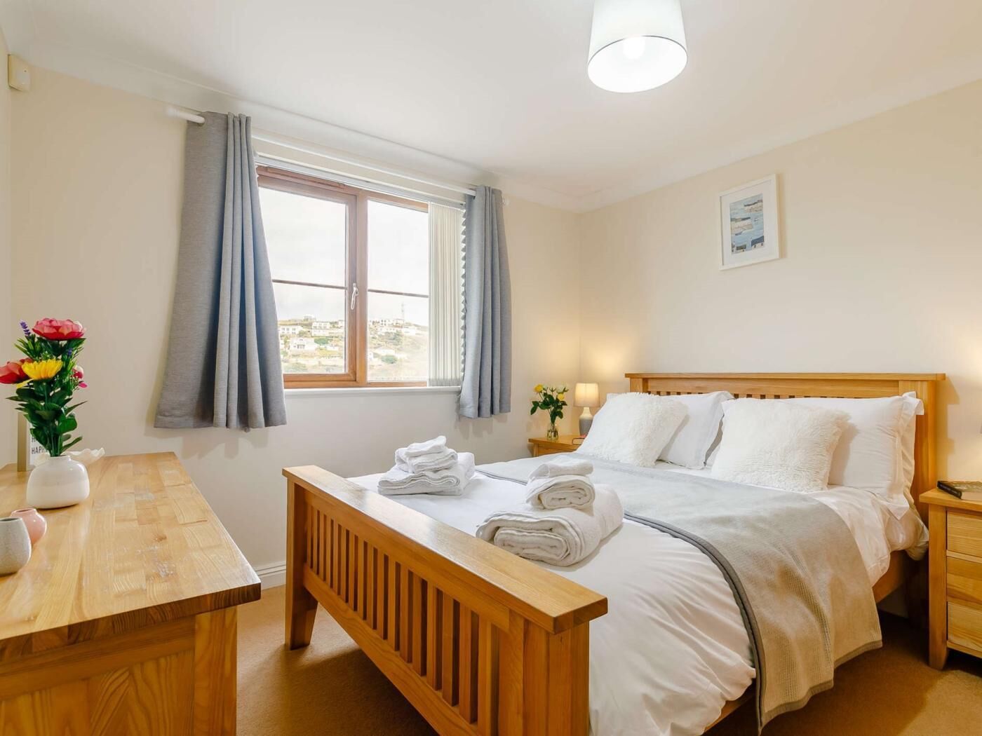 A hotel room with a bed, bedside table, and a window with curtains.