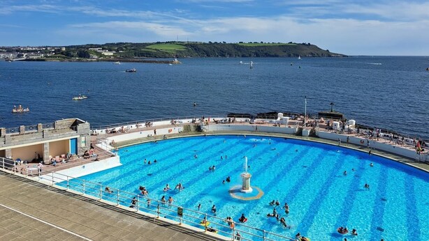 Ein großer Pool im Freien mit einer Fontäne, umgeben von einer Sonnenterrasse mit Sitzbereichen und Blick aufs Meer.