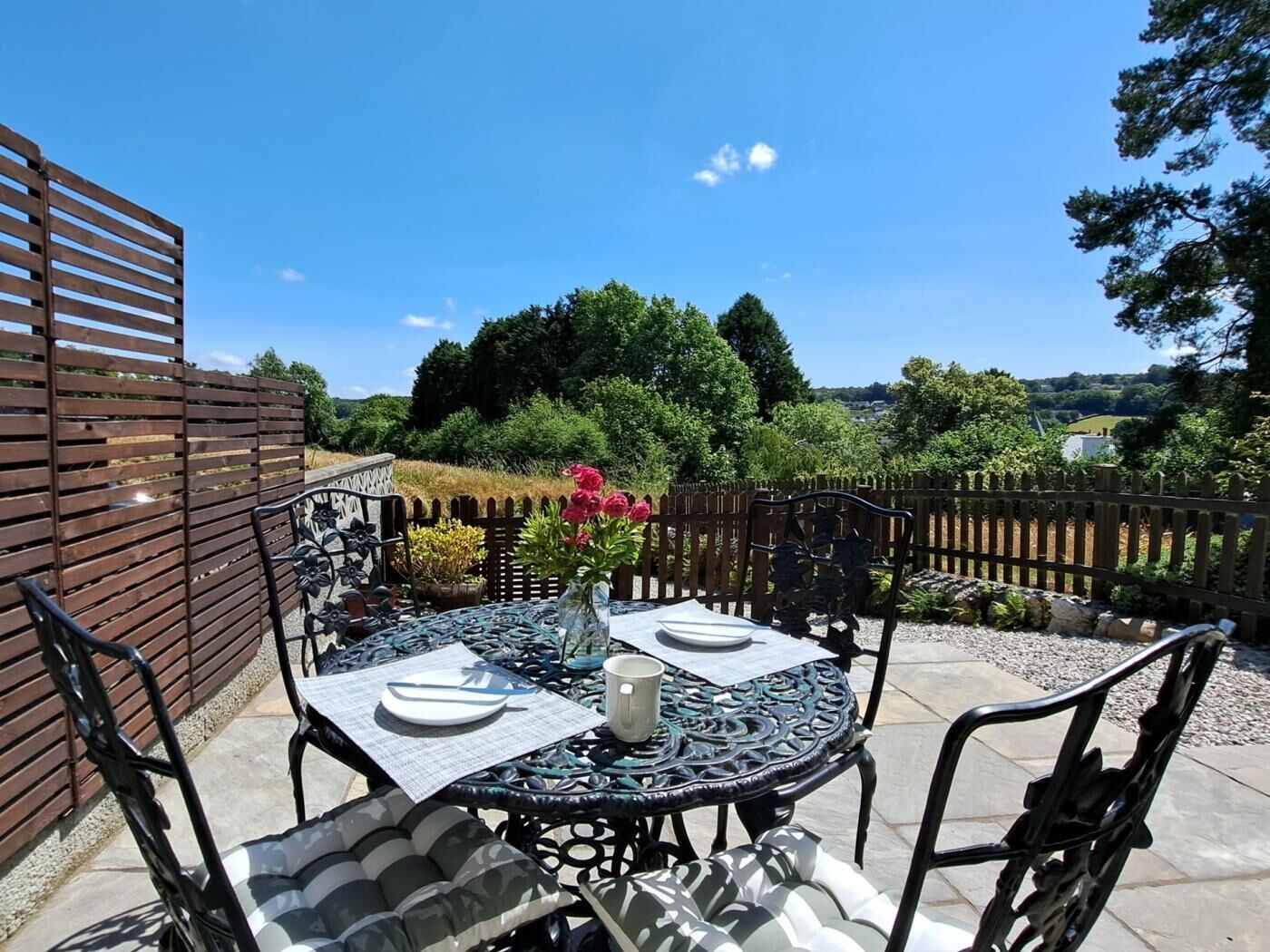 An outdoor patio with a round table, chairs, and a decorative fence.