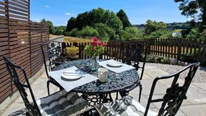 Eine Terrasse im Freien mit einem runden Tisch, Stühlen und einem Zierzaun.