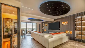 Ein modernes Wohnzimmer mit einer großen Couch, einem Flachbildfernseher und einem einzigartigen Himmel mit Sternenmuster an der Decke.