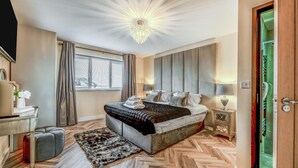 Ein modernes Schlafzimmer mit einem großen Bett, einem Schreibtisch, einem Sessel, einem Teppich und einer Chandelier.