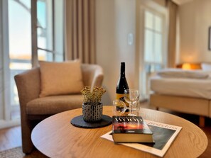 Une table ronde en bois, sur laquelle se trouvent un livre, une bouteille et un verre.