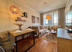 Un salon moderne comprenant un coin repas, un canapé, une table basse et un téléviseur.