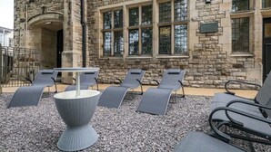 Un bâtiment en pierre doté d’une cour intérieure aménagée avec des sièges et une table pour l’extérieur.