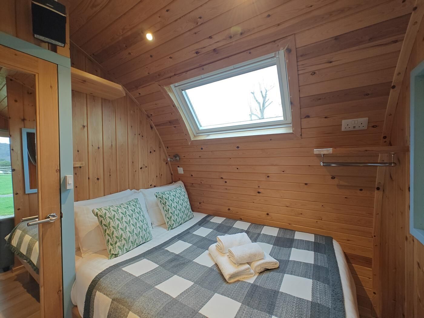 Ein Zimmer mit Holzwänden, einem Bett, einem Fenster und einer Tür.