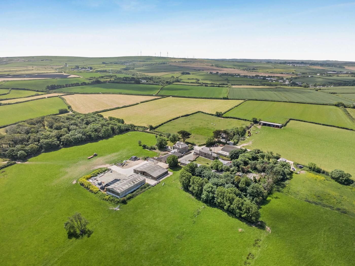 An aerial view of a rural property with fields, a large building complex, and scattered trees.