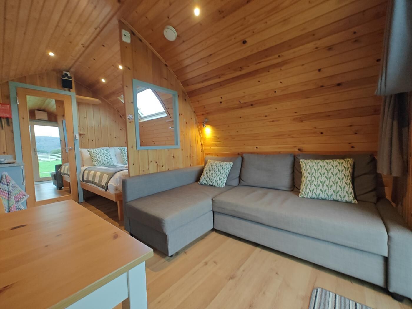 Un intérieur de chalet chaleureux avec un canapé, une table et une vue sur l’extérieur.