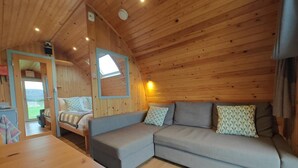 A cozy cabin interior with a sofa, a table, and a view of the outdoors. - 1 Bed in Tyn-y-Groes (oc-g36301) (Ty'n-y-groes)
