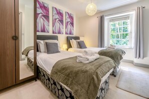 A hotel room with two beds, a large window with curtains, and artwork on the wall. - 5 Bed in St. Agnes (oc-q37500) (Saint Agnes)