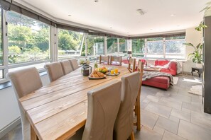 A modern dining area with a wooden table, chairs, and a red sofa. - 5 Bed in St. Agnes (oc-q37500) (Saint Agnes)