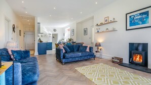 Un salon avec une cheminée, un canapé, une table basse et un tapis à motifs.