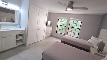 A bedroom with a bed, a dresser, a vanity, and a ceiling fan.