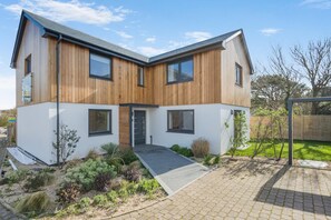 Ein modernes, zweistöckiges Haus mit Flachdach, großen Fenstern und einem Eingang.