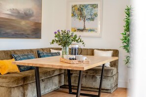 A living room with a wooden coffee table, a sofa, and a painting on the wall. - 4 Bed in Padstow (oc-p36067) (Constantine Bay)