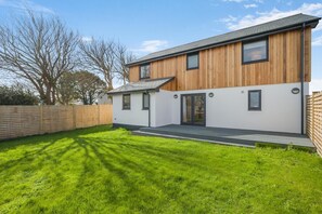 Ein modernes, zweistöckiges Haus mit Holzfassade und einem gepflegten Rasen.