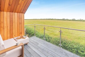 A wooden deck with a white sofa and a tray of breakfast items. - 3 Bed in Padstow (oc-p36068) (Constantine Bay)